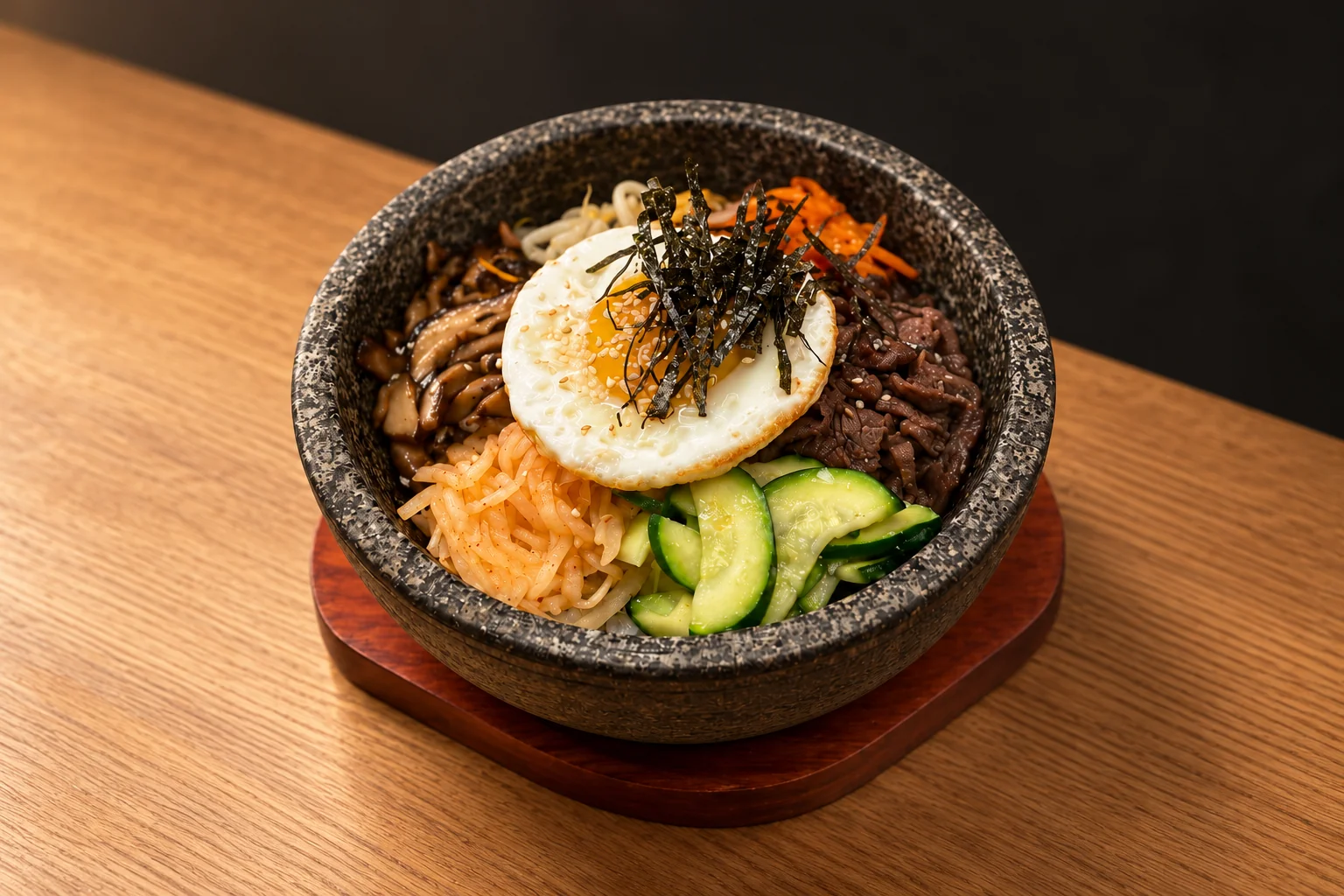 Stone bowl with vegetables, meat, a fried egg and seaweed.